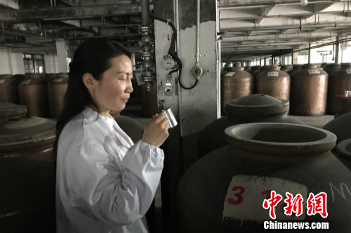 高玲在品尝装在酒缸里的原酒。中新网 种卿 摄