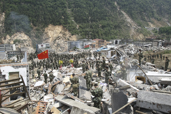 2008年5月，北川羌族自治县，参加救援的官兵站在废墟上，庄重地脱下帽子，面朝半旗，默哀。 澎湃新闻 资料