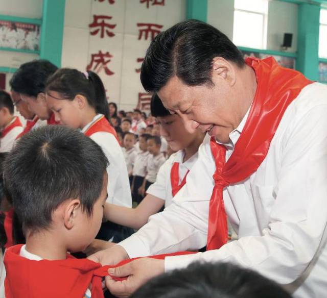 2014年5月30日，习近平来到北京市海淀区民族小学参加庆祝“六一”国际儿童节活动。这是习近平在少先队入队仪式上，为新少先队员系上红领巾 鞠鹏摄/本刊