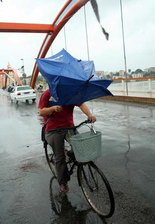 福州市区风雨交加,一名市民撑伞骑车路过解放大桥