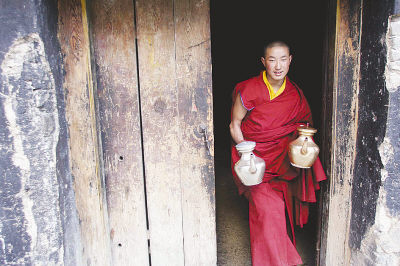 木里大寺里的年轻喇嘛在为寺庙颂经的喇嘛送茶.