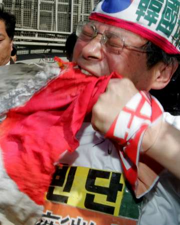 愤怒的韩国普通民众在咬日本国旗