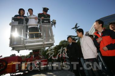 昨天，东城区地坛体育馆前，市民亲身体验了一把坐上专业消防高空云梯车升空的感觉