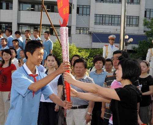 李宇轩(前左)从乌鲁木齐第十三中学校长高喜梅手中接过"奥运火炬"