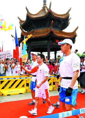5月31日，奥运火炬手杨威（中）手持火炬传递。　　新华社记者 程敏摄 