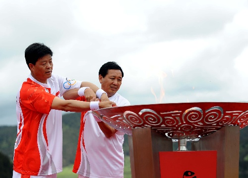 6月11日，奥运火炬手彭耀文（左）与张国伟共同点燃圣火盆。当日，北京奥运圣火在云南香格里拉传递。