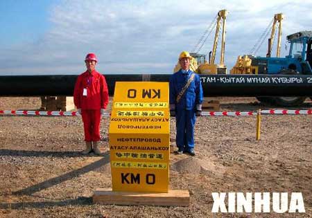 这是身着红衣的中国施工人员与身着蓝衣的哈萨克斯坦施工人员站在位于哈境内的中哈石油管道首站零公里处。 新华社记者陈俊锋摄