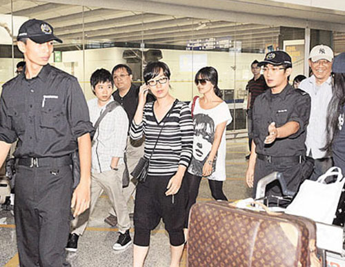宋慧乔在工作人员护送下走出机场，面无表情