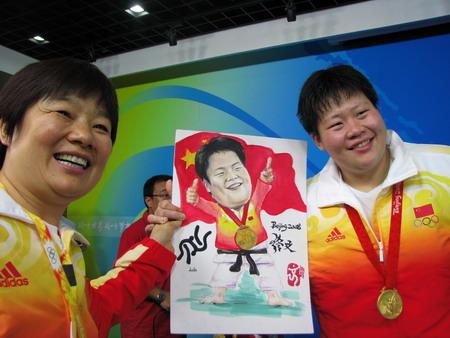 图为夺冠后佟文与教练拿着观众为她画的漫画合影
