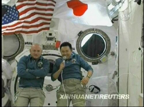 “发现”号机组指令长马克·凯利（左）和日本宇航员星出彰彦在国际空间站上的“希望”号实验舱内回答日本官员的提问（美国宇航局6月7日电视画面）。新华社/路透