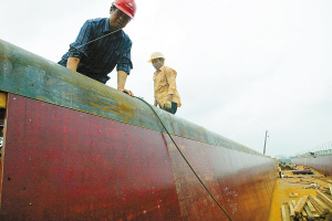 在东环铁路海口新建高架特大桥工地，工人们将木制水泥夹板集中整固，以免被风吹走。 本报记者 古月 摄