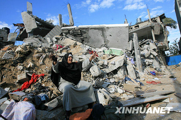 1月3日,在加沙地带南部城镇拉法,一名妇女坐在被以色列军队空袭促毁