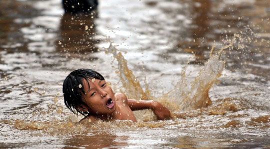 1月14日,在印度尼西亚首都雅加达市中心,一名男孩在暴雨过后被水淹
