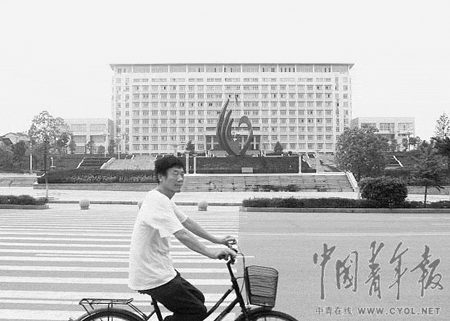 一名骑车人从麻城市政府楼前经过，不远处是城标雕塑。 本报记者 雷宇摄 