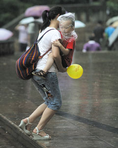 昨日,江北,大人怀中的小孩头戴塑料袋遮雨 记者 刘嵩 摄