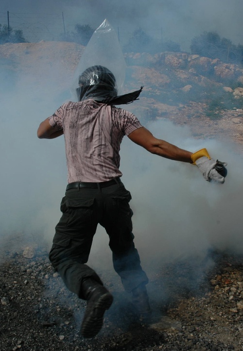 附近的村庄比林,一名巴勒斯坦抗议者把催泪弹的弹壳向以色列士兵掷回