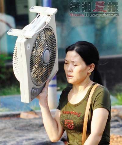 近日，人民路，一女士手举电扇匆匆而过。此时这台电扇不能给她扇风，但可以给她遮阳。图/摄友团卢七星