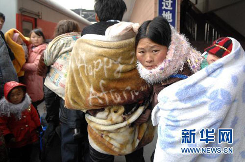 1月18日,几位前往贵阳的外来务工者背着孩子在站台候车.