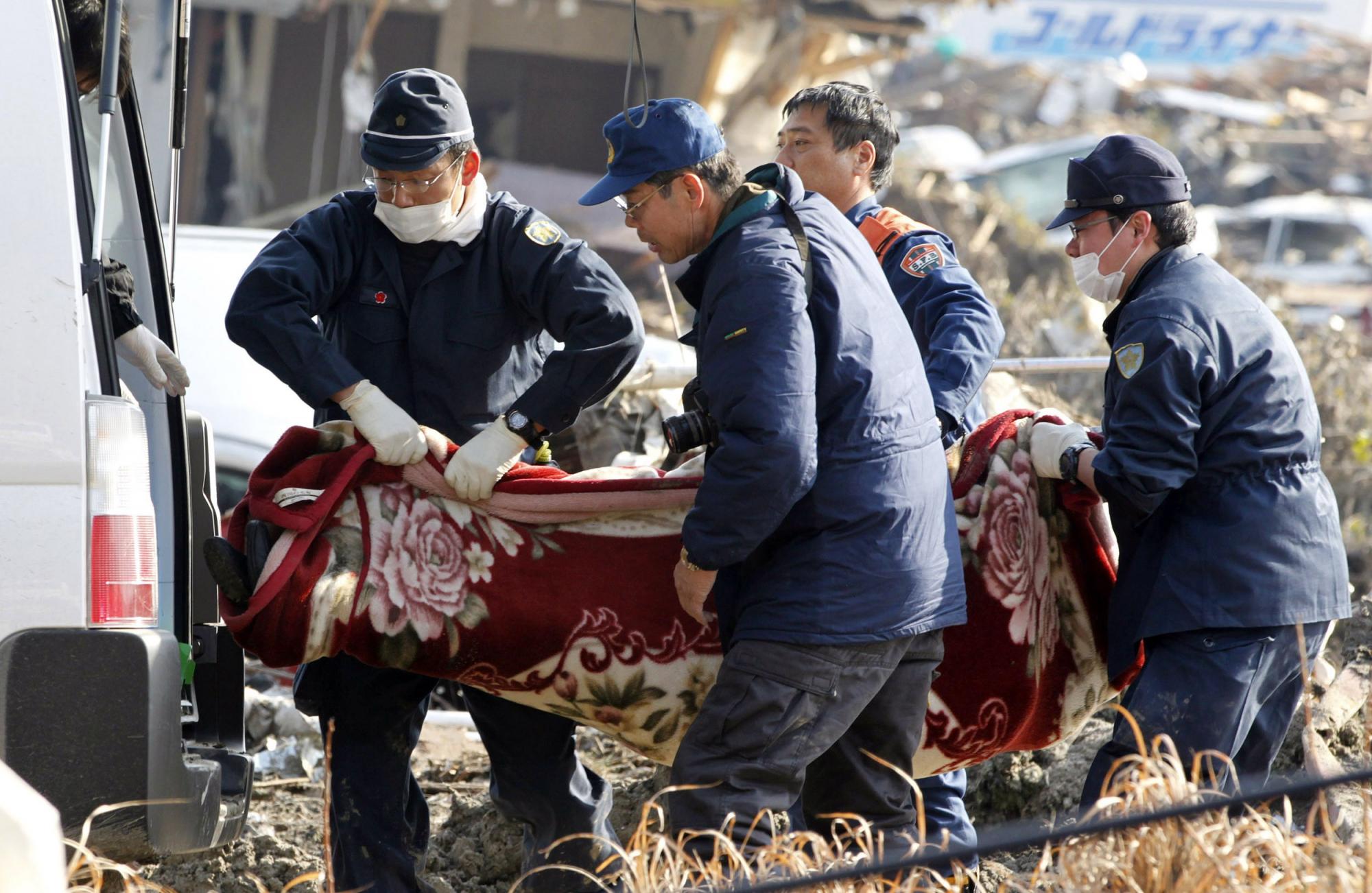 在仙台市地震现场,几名救援人员正在将遇难者的尸体运走