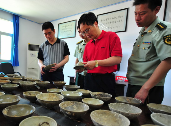 图为文物专家及边防官兵正在察看查获的古代瓷碗.摄影:林若伟