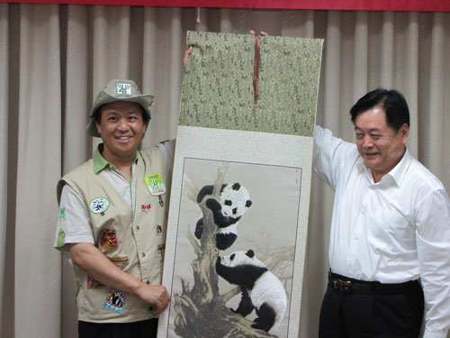 蒋巨峰(右)向台北动物园园长叶杰生致赠熊猫图样的蜀绣。 吴亚明摄