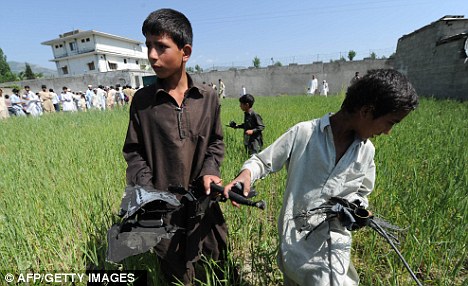 一些巴基斯坦小孩在飞机残骸附近玩耍并拾拣残骸。