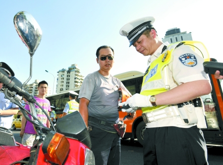 高晓东（右）对摩托车驾驶员进行例行检查 记者 徐元宾 摄