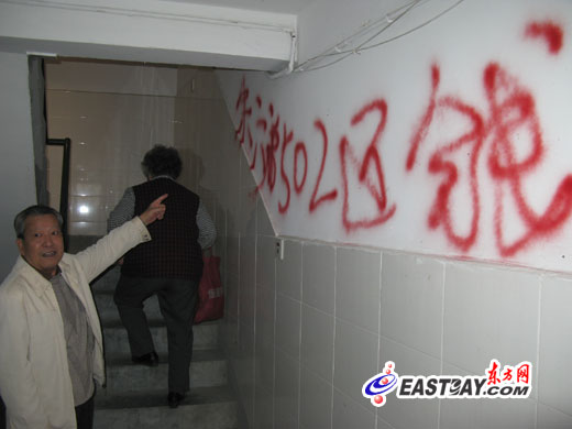 图片说明:楼道内,赫然被人用红色油漆喷涂了"朱某某骗钱"欠债还钱"