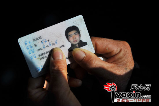 图为11月21日,冯战明富民手里握着儿子的身份证,这张身份证是他留下的
