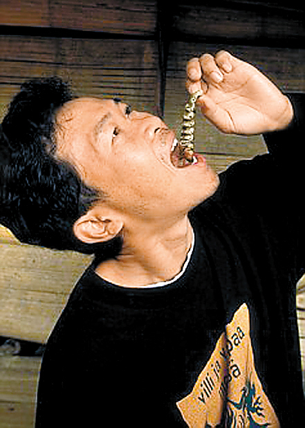 一名泰国导游正在向游客演示吃蠕虫的过程