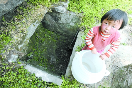 一个小女孩站在干枯的水井旁