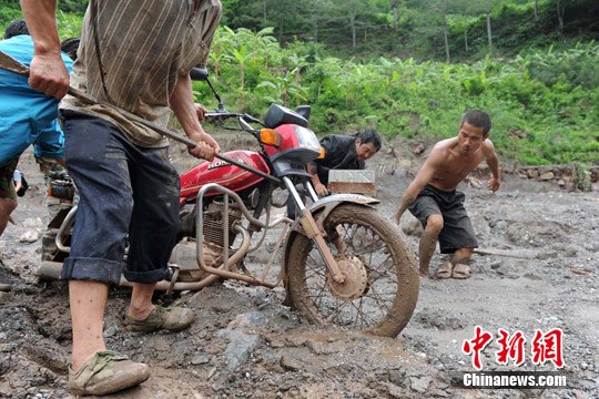 村民用钢筋协助摩托车“过河”。 张浪 摄