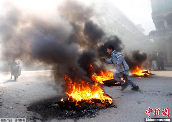 当地时间2012年2月22日，阿富汗民众针对驻阿美军士兵焚烧古兰经的抗议示威活持续升级。示威民众在首都喀布尔与警察冲突，并发生枪击事件。图为一名男孩从火堆旁跑过。
