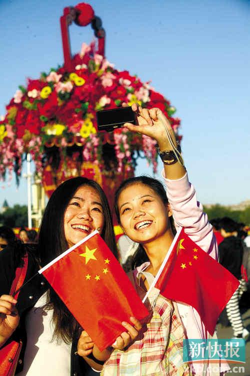 两名女孩手拿小国旗在北京天安门广场拍照留念新华社发