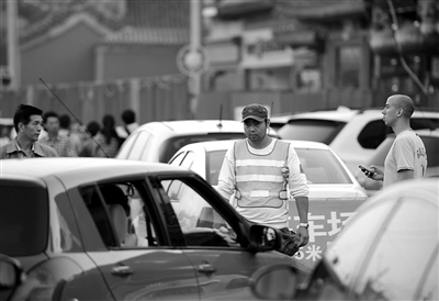 昨日，地安门外大街，一名未穿制服的男子指挥车辆停车并收取停车费。