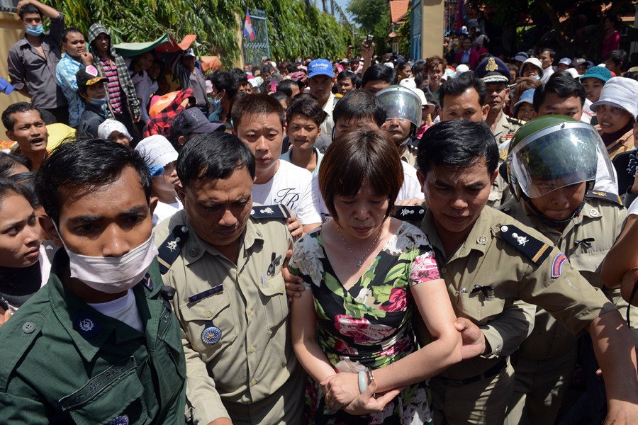 当地时间10月22日，柬埔寨逾千人在金边王宫游行，抗议一家柬埔寨服装厂的一位中国籍女性管理员由于员工“怠工”，撕毁柬前国王西哈努克画像。图为警方将该中国籍女子带去画像前道歉。