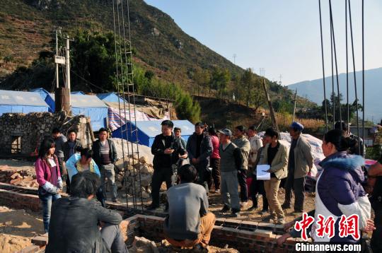 图为技术人员现场指导村民重建新房。彭洪摄