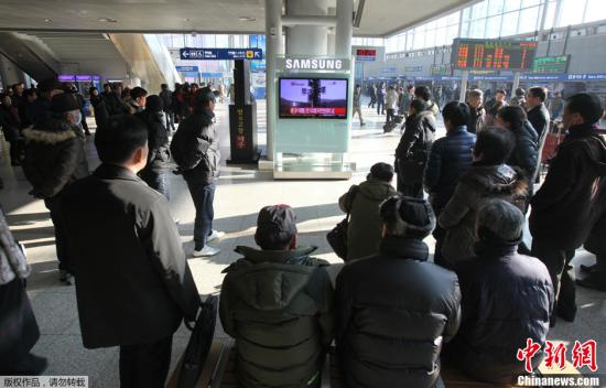 2012年12月12日，韩国首尔火车站，韩国民众观看电视中播放的关于朝鲜火箭发射的报道画面。屏幕下面显示：“朝鲜的火箭发射似乎是成功的。”