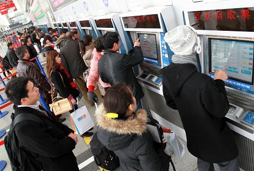 12月25日，旅客在上海火车站自助售票处取票。新华社发（丁汀摄）
