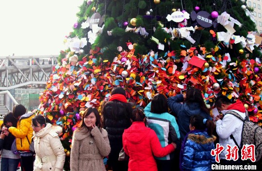 节之际,在北京繁华的西单街头众多男女青年在巨大的圣诞树上挂上许愿