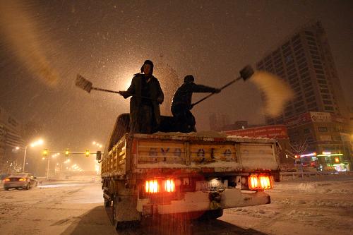 1月2日，道路养护工人在山东省烟台市南大街抛撒融雪剂。新华社发(申吉忠 摄)