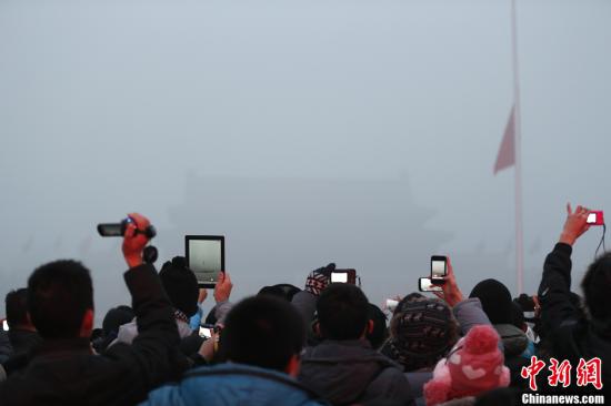 1月29日晨，北京天安门广场上民众在大雾中观看升国旗仪式。当日北京雾霾天持续，空气严重污染。中新社发 盛佳鹏 摄