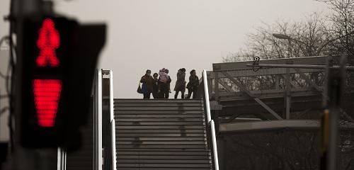 3月9日，路人在大风中从西单的人行天桥上走过。新华社记者 费茂华 摄