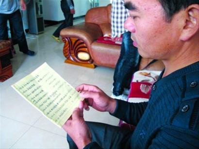 去年，文氏四兄弟在桂林全城寻找母亲，图为当时记者前往采访时，文石明在阅读记录线索的本子。/晨报记者张岂凡