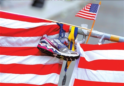 4月18日，市民将一双写有爆炸案时间的跑鞋和一枚波士顿马拉松赛的奖牌挂在悼念现场。　　新华社发