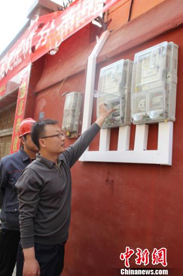 保定市民张俊凯在供电公司工作人员指导下将电闸推合，这标志着河北省首个家用分布式光伏发电系统并网成功。　于俊亮　摄
