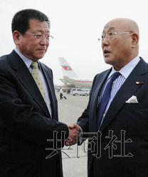 5月14日，日本内阁官房参事饭岛勋（右）抵达平壤，在机场与前来迎接的朝鲜外务省亚洲局副局长金哲虎握手。（共同社）