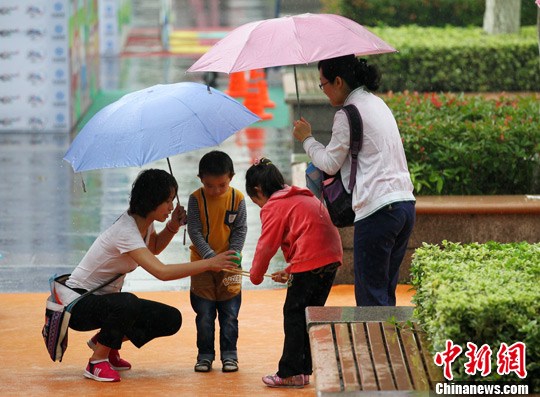 孩子雨中过六一 家长打伞护左右(图)