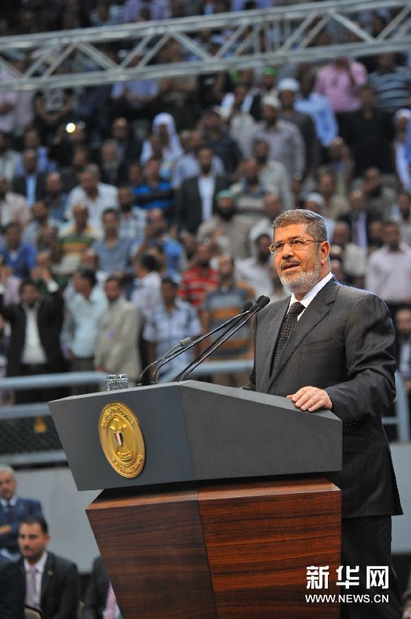 这是2013年6月15日埃及总统穆尔西（中）在埃及开罗国家体育馆叙利亚问题大会上同民众致意的照片。