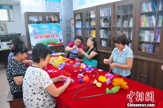 广西柳州车辆厂社区在社区统战工作站的民族女子手工作坊继续开展各类技能培训活动，帮助下岗失业的妇女再就业。图为妇女在进行珠绣。